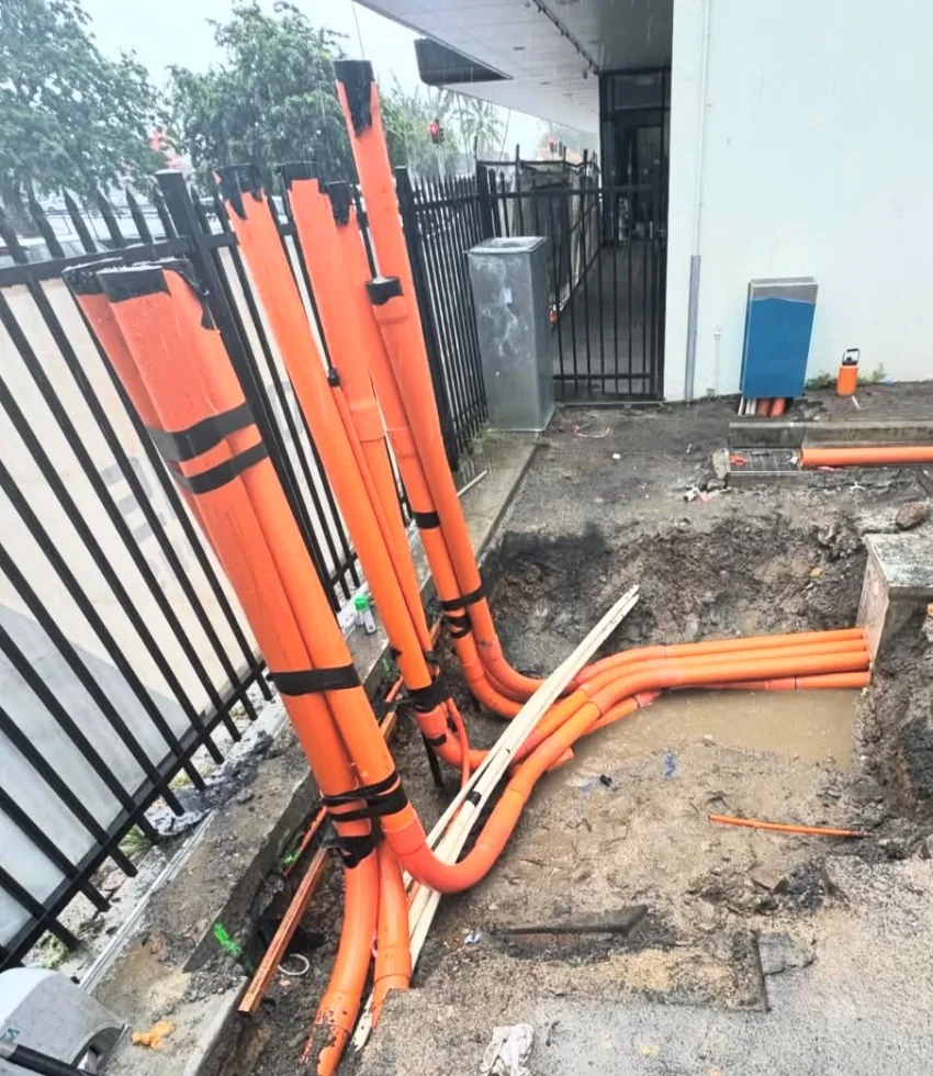 Closer view of orange conduits running through the excavation at the same site